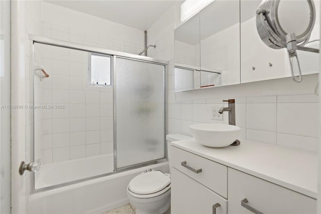 bathroom with tasteful backsplash, shower / bath combination with glass door, vanity, and toilet