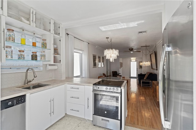 kitchen with a sink, stainless steel appliances, light countertops, and white cabinets