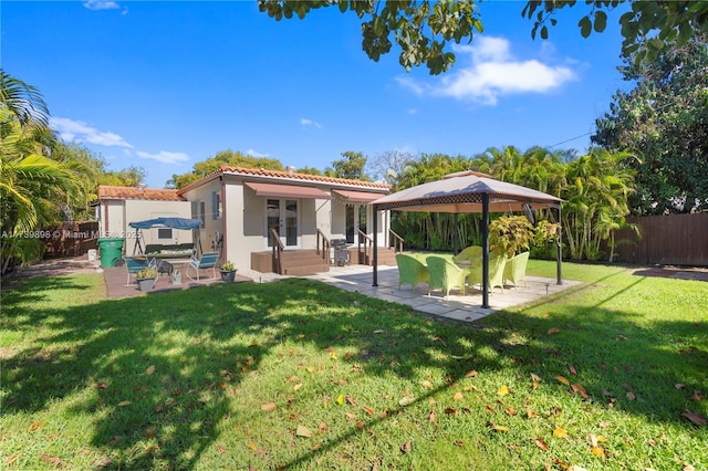 back of house featuring a yard, a tile roof, fence, and stucco siding