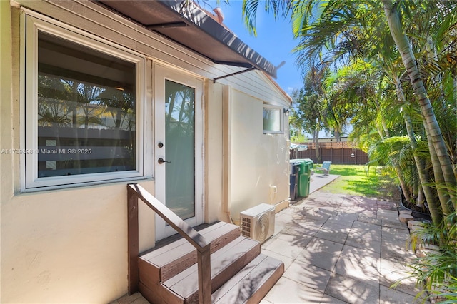 doorway to property with fence, a patio, and stucco siding