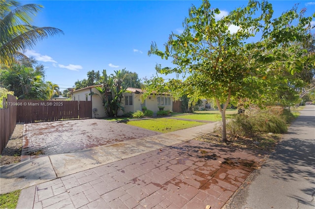 view of front of property with driveway, a front yard, fence, and stucco siding