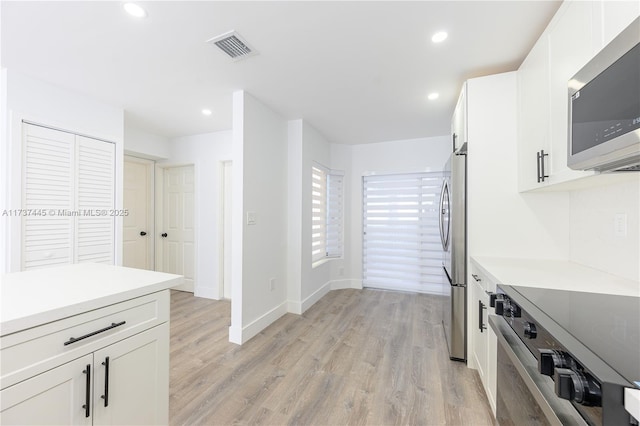 kitchen with stainless steel appliances, light wood-type flooring, and white cabinets