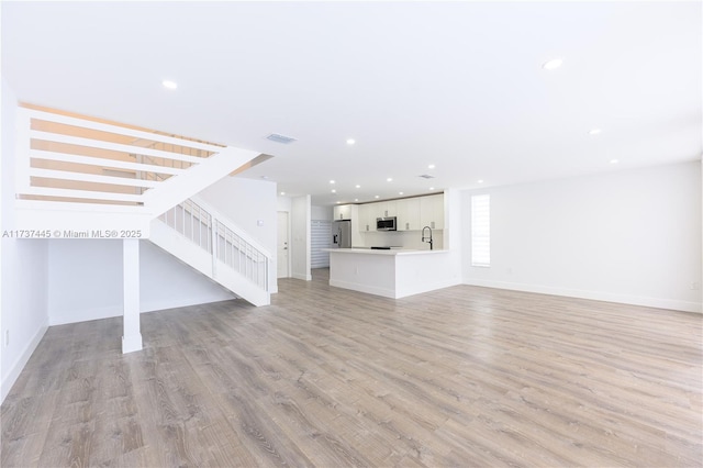 unfurnished living room with sink and light wood-type flooring