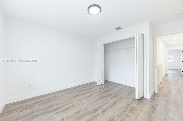 unfurnished bedroom with light hardwood / wood-style flooring and a closet