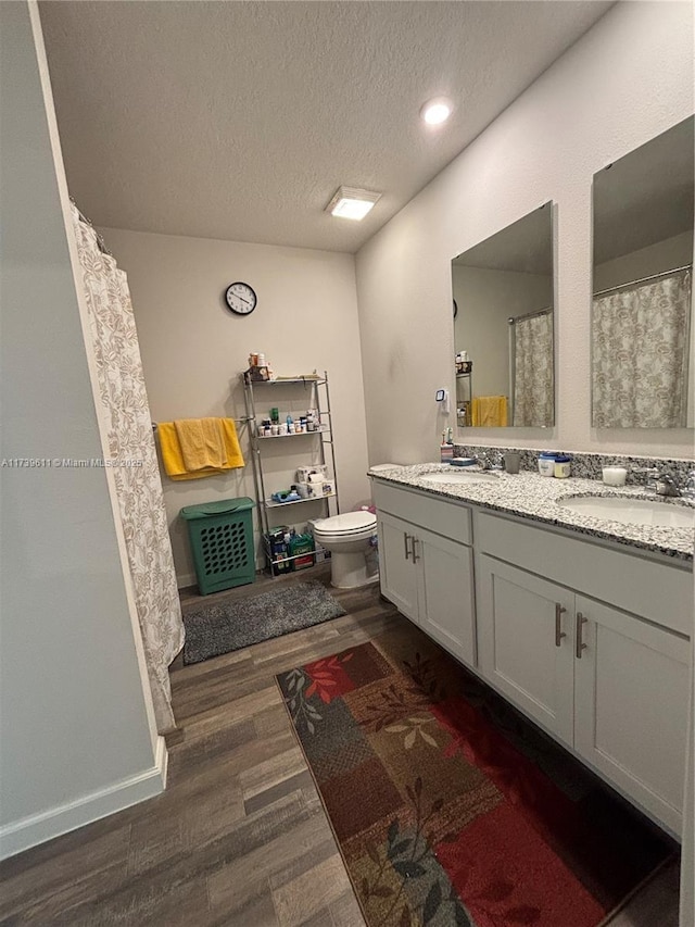 bathroom with hardwood / wood-style flooring, vanity, a textured ceiling, and toilet