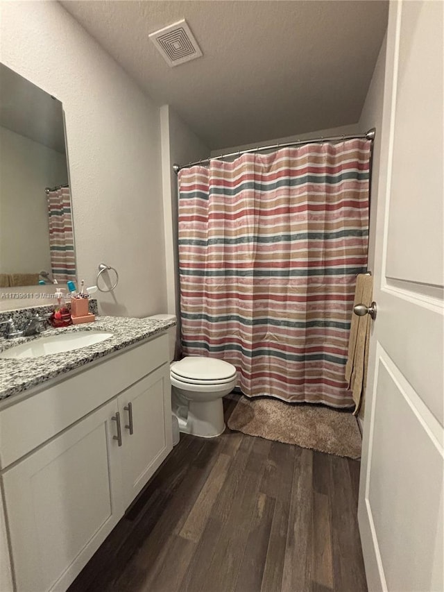 bathroom with hardwood / wood-style flooring, vanity, a textured ceiling, and toilet