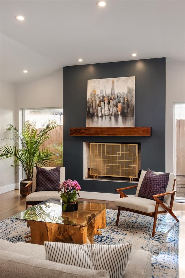 interior space with wood-type flooring, a fireplace, and vaulted ceiling