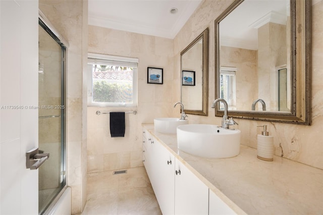 bathroom featuring ornamental molding, tile walls, vanity, and shower / bath combination with glass door