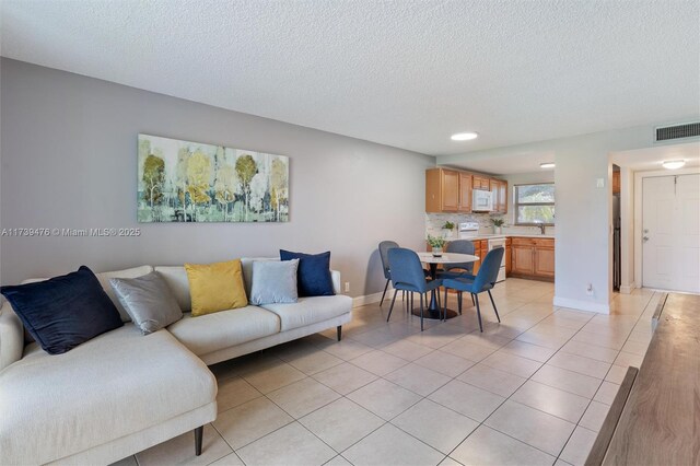 living room featuring light tile patterned floors, sink, and a textured ceiling