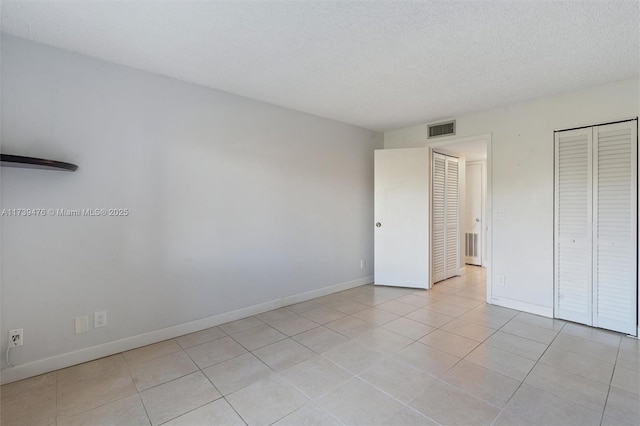 unfurnished bedroom featuring light tile patterned floors, a closet, and a textured ceiling