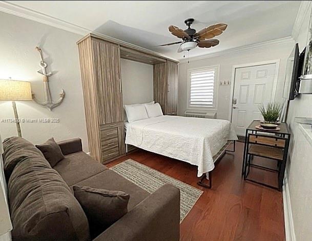 bedroom featuring dark hardwood / wood-style flooring, crown molding, and ceiling fan