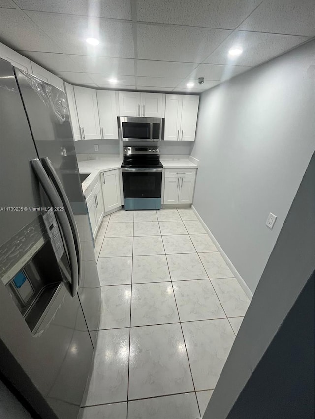 kitchen featuring white cabinetry, light tile patterned floors, a drop ceiling, and appliances with stainless steel finishes