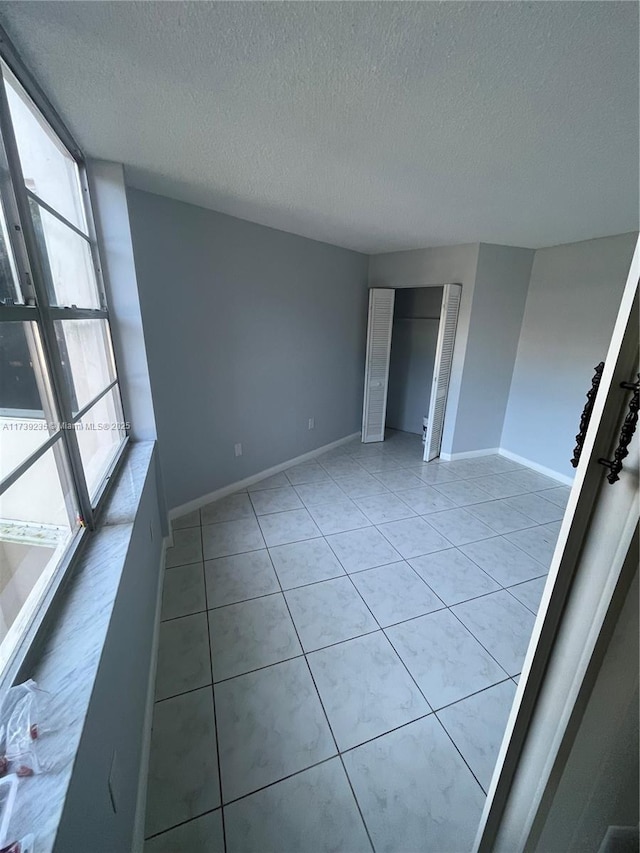 tiled spare room featuring a textured ceiling