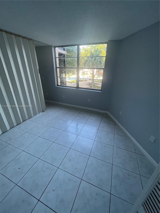 tiled empty room featuring a textured ceiling