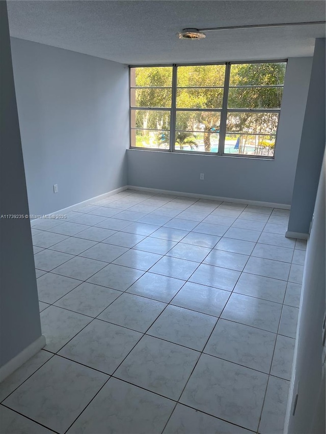 tiled empty room featuring a textured ceiling