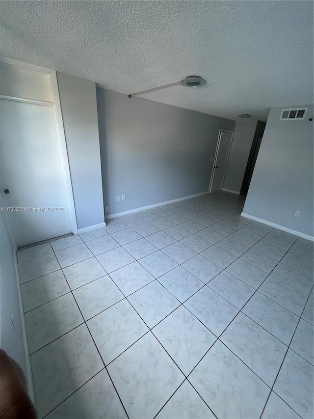 spare room featuring light tile patterned flooring and a textured ceiling