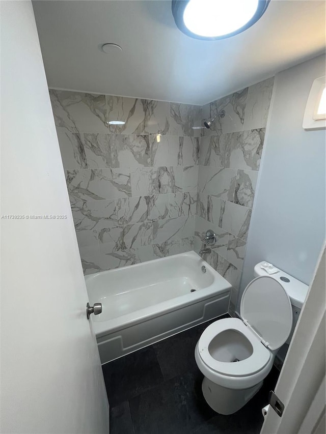 bathroom featuring tiled shower / bath combo and toilet