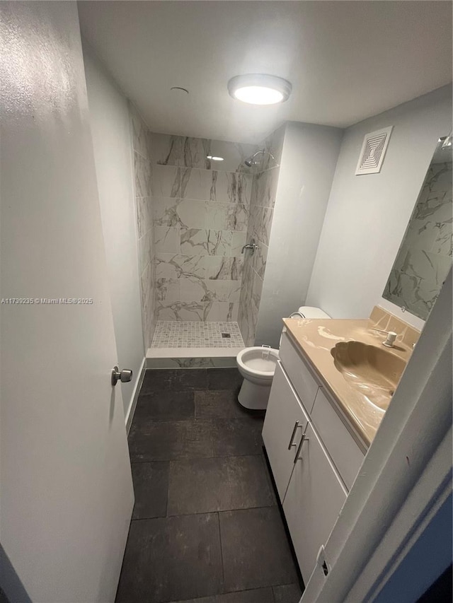 bathroom featuring vanity, a tile shower, and toilet