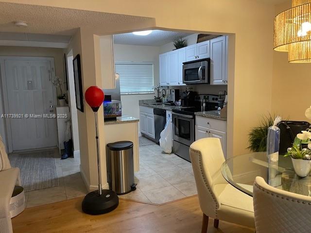 kitchen with sink, decorative light fixtures, stainless steel appliances, light hardwood / wood-style floors, and white cabinets