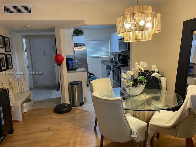 dining space with a notable chandelier and light hardwood / wood-style flooring