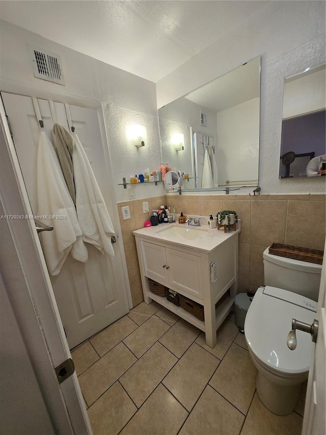 bathroom with tile patterned flooring, vanity, tile walls, and toilet