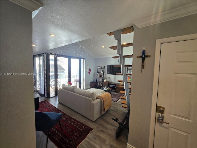 living room with crown molding, vaulted ceiling, hardwood / wood-style floors, and a textured ceiling