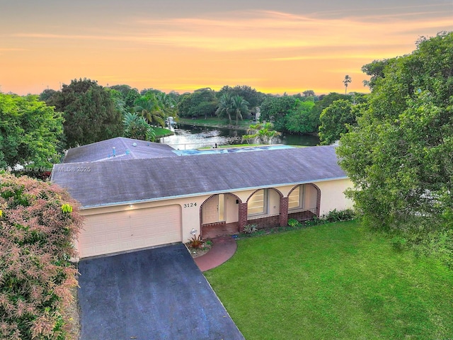 single story home featuring a garage, a water view, and a yard