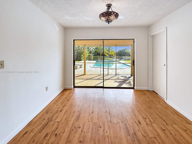 unfurnished room with light hardwood / wood-style floors and a textured ceiling