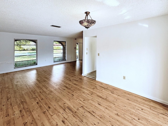 unfurnished room with light hardwood / wood-style floors and a textured ceiling