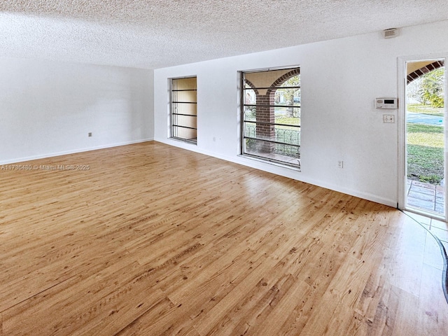 unfurnished room featuring light wood-type flooring, a textured ceiling, and built in shelves