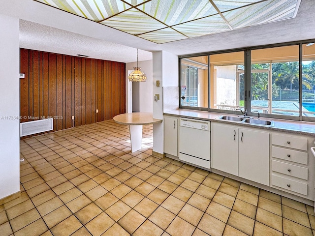 kitchen with wooden walls, decorative light fixtures, sink, white cabinets, and white dishwasher