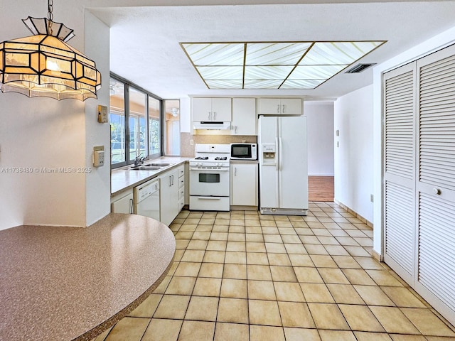 kitchen with light tile patterned flooring, sink, decorative light fixtures, white appliances, and white cabinets