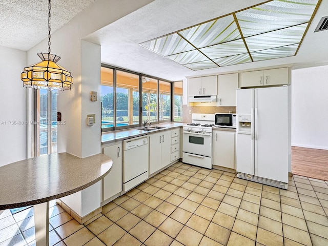 kitchen featuring sink, white appliances, white cabinetry, hanging light fixtures, and a textured ceiling