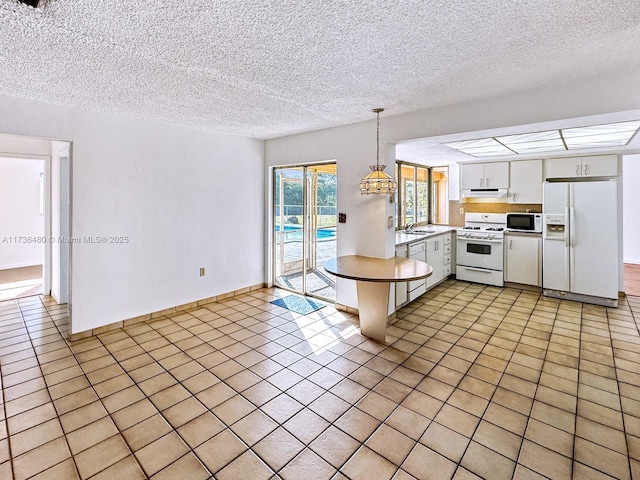 kitchen featuring white cabinetry, light tile patterned floors, white appliances, and decorative light fixtures