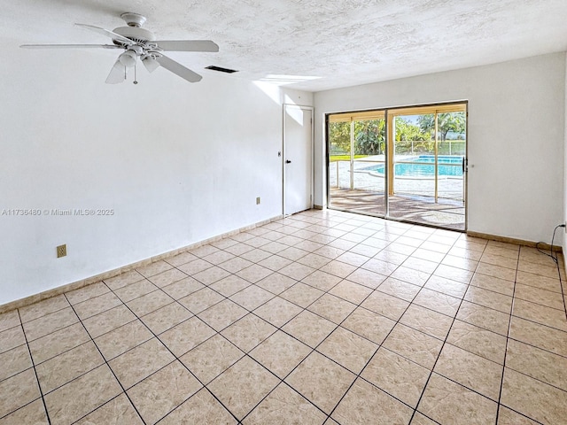 empty room featuring light tile patterned flooring, ceiling fan, and a textured ceiling