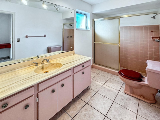 bathroom featuring walk in shower, vanity, toilet, and tile patterned flooring