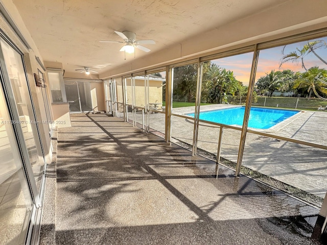 pool at dusk with ceiling fan and a patio area