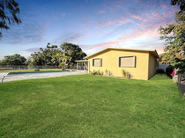 yard at dusk featuring a fenced in pool