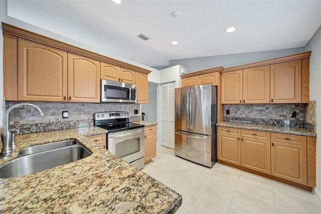 kitchen featuring appliances with stainless steel finishes, sink, light stone counters, and decorative backsplash