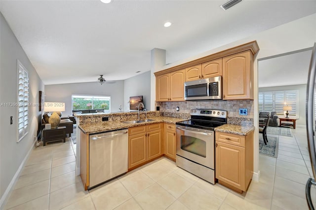 kitchen featuring appliances with stainless steel finishes, sink, light stone counters, and kitchen peninsula