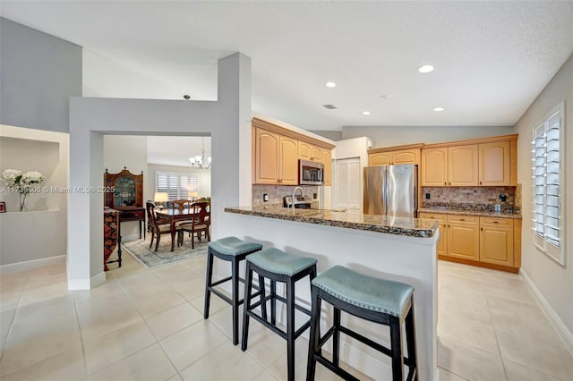 kitchen with stone countertops, light brown cabinetry, vaulted ceiling, and appliances with stainless steel finishes