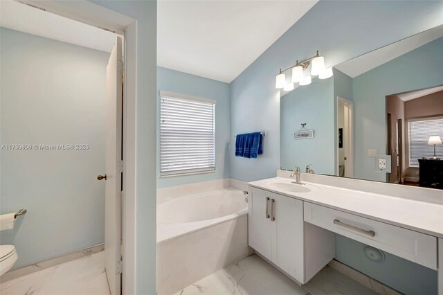 bathroom featuring a washtub, vanity, lofted ceiling, and toilet