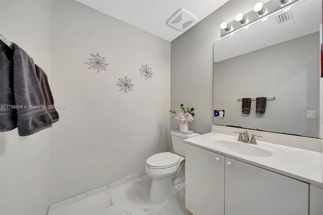 bathroom with vanity, toilet, and a textured ceiling