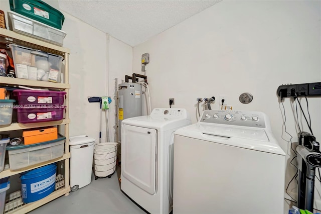 washroom featuring independent washer and dryer, water heater, and a textured ceiling