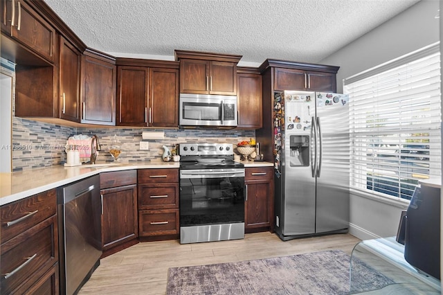 kitchen featuring backsplash, stainless steel appliances, sink, and light wood-type flooring