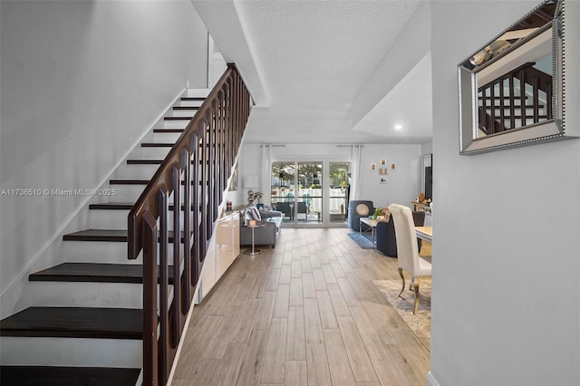 stairway with wood-type flooring and a textured ceiling