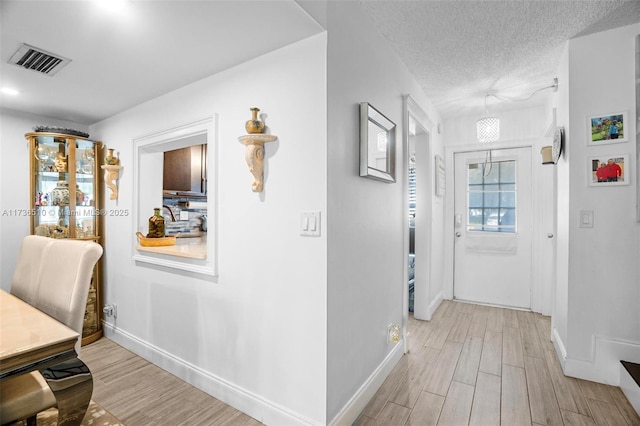 hall with light hardwood / wood-style flooring and a textured ceiling