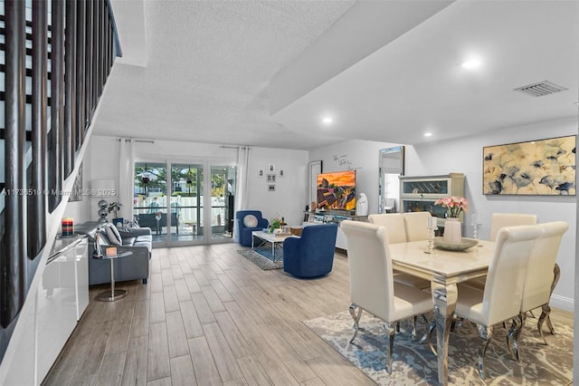 dining space featuring a textured ceiling and light hardwood / wood-style flooring