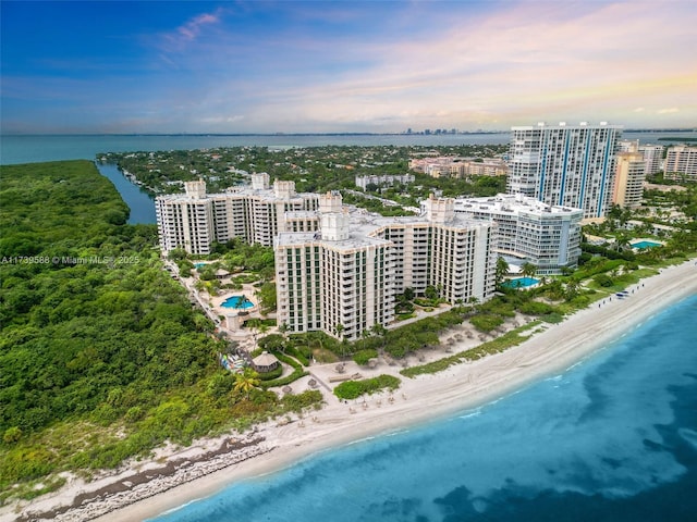 aerial view at dusk with a view of the beach and a water view