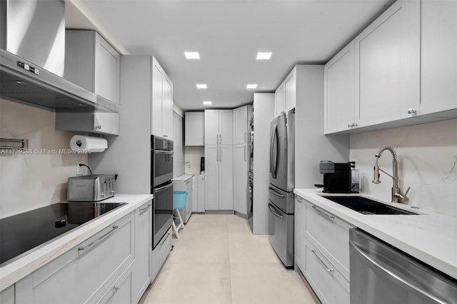 kitchen with wall chimney exhaust hood, sink, white cabinetry, appliances with stainless steel finishes, and backsplash